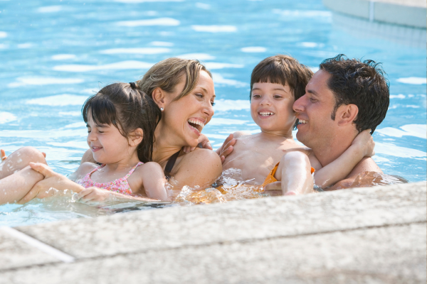Smiling family of four in a swimming pool